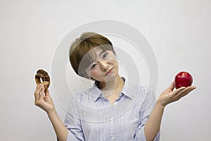 Young woman holding an apple and a doughnut