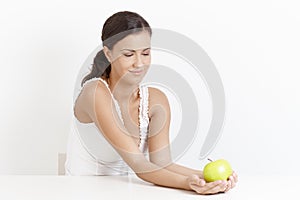 Young woman holding apple over white smiling