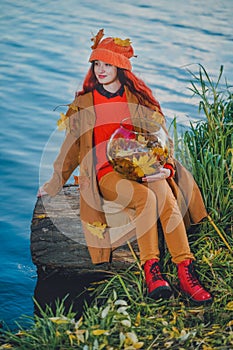 Young woman holding an aquarium with maple leaves in autumn. Concept