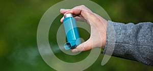 Young woman holding an astma inhaler against attacks in her hands, healthcare concept