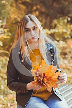 Young woman holding autumn leaves in fall park. Seasonal, lifestyle and leisure concept.