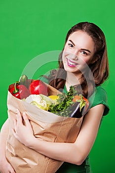 Young woman holding a bag full of healthy food.