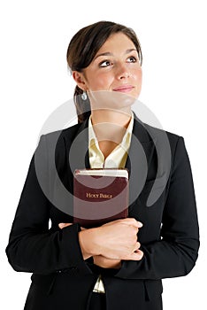 Young woman holding a bible whilst looking up