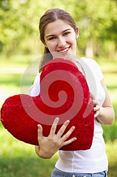 Young woman holding big red heart