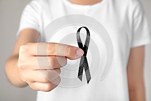 Young woman holding black ribbon. Funeral symbol