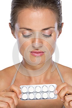 Young woman holding blistering package of pills