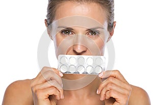 Young woman holding blistering package of pills