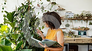 Young woman holding a book and observe a plant