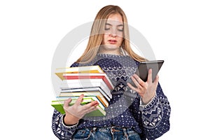 Young woman holding books and reading an ebook reader.