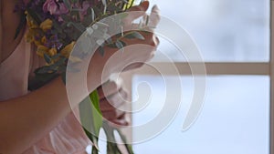 Young woman holding a bouquet of spring flowers in the light of the morning sun. Slow motion