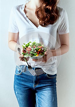 Young woman holding a bowl of healthy arugula and cherry tomato salad