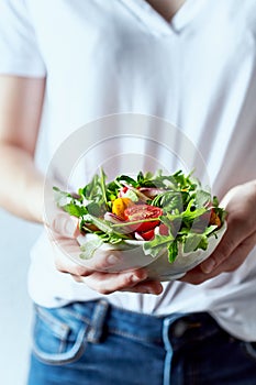 Young woman holding a bowl of healthy arugula and cherry tomato salad