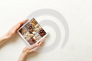 Young woman holding box with different nuts, closeup. Close up, copy space, top view, flat lay. Walnut, pistachios