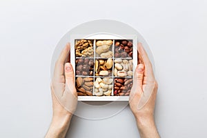 Young woman holding box with different nuts, closeup. Close up, copy space, top view, flat lay. Walnut, pistachios