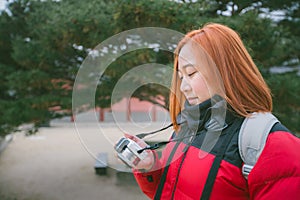 Young woman holding camera in hand. photographer woman with camera looking photos on camera.