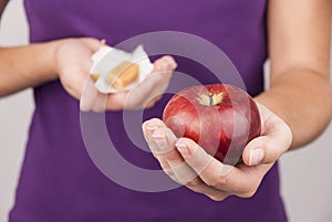 Young woman holding candy and apple
