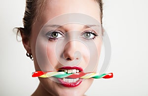 Young woman holding candy in her teeth
