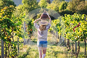 Young woman holding carboy with wine in vineyard