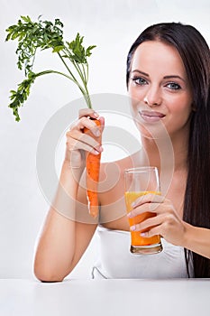 Young woman holding carrot and carrot juice