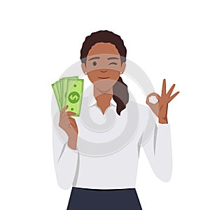 Young woman holding cash or currency or money in hand and showing OKAY or OK sign