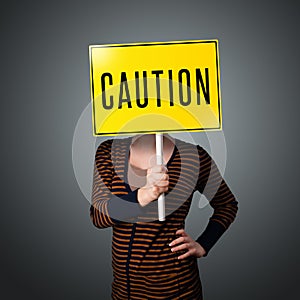Young woman holding a caution sign