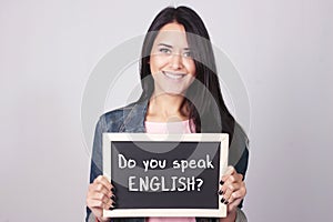 Young woman holding chalkboard that says Do You Speak English?