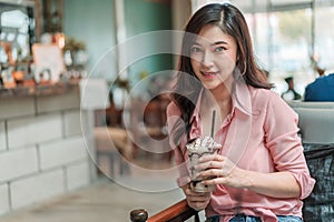 Woman holding chocolate frappe with whipped cream in the cafe photo