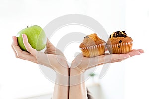 Young woman holding and choosing fruit and sweet at home.