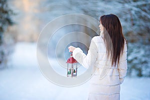 Young woman holding Christmas lantern outdoors on beautiful winter snow day