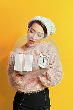 Young woman holding a clock showing nearly 12