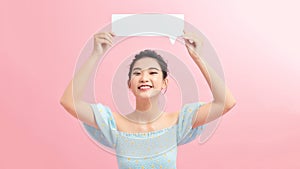 Young woman holding cloud speech bubble standing over isolated pink background with a happy face