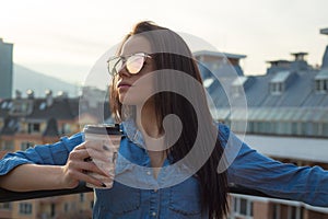 Young woman holding coffee cup on balcony