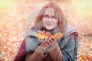 A young woman holding colored leaves. Girl in autumn coat and scarf with beautiful leaves on the palm