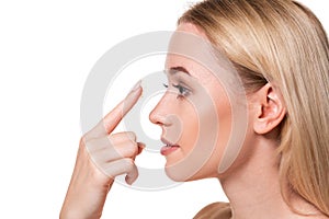 Young woman holding contact lens on index finger with copy space. Close up face of healthy beautiful woman about to wear