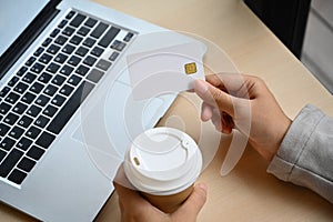 Young woman holding credit card making purchase, payments on web stores via laptop computer