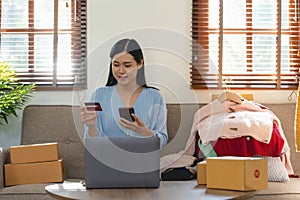 Young woman holding credit card for shopping online with computer while sitting in the living room at home. black friday