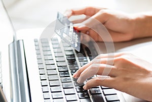 Young woman holding a credit card and typing