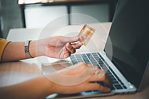 Young woman holding credit card and using laptop computer. Businesswoman working at cafe. Online shopping, e-commerce, internet