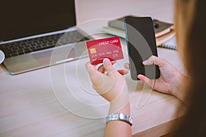 Young woman holding credit card and using laptop computer. Businesswoman working at cafe. Online shopping, e-commerce, internet