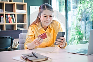 Young woman holding credit card and using laptop computer. Businesswoman working at cafe. Online shopping, e-commerce, internet