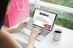 Young woman holding credit card and using laptop computer in cafe. Online shopping concept