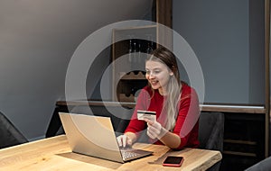 Young woman holding credit card and using laptop computer. Girl working online. Online shopping, e-commerce, internet banking,