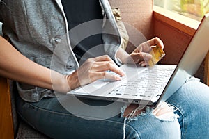 Young woman holding credit card and using laptop computer. Online shopping
