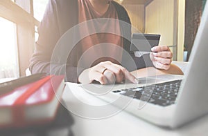 Young woman holding credit card and using laptop computer. Online shopping concept