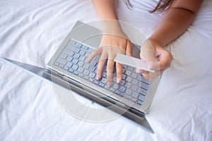 Young woman holding credit card and using laptop computer for shopping online at home.Online shopping, e-commerce