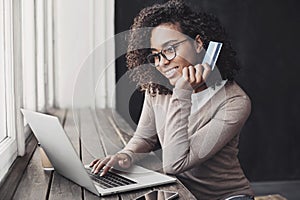 Young woman holding credit card and using laptop making payment online. Businesswoman or entrepreneur working at home