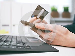 Young woman holding credit card and using laptop and smartphone. Online shopping, booking and banking concept. Businesswoman or