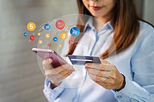 Young woman holding a credit card and using smartphone for making online payment shopping