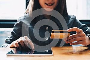 Young woman holding credit card and using tablet computer. Online shopping concept