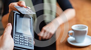Young woman holding credit doing wireless bank payment with POS terminal process acquire at table in coffee shop cafe restaurant